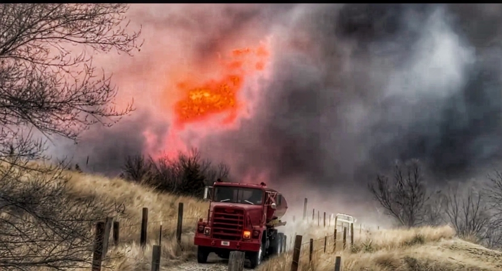 Cottonwood Wildfire burning with a volunteer fire truck driving away from the flames